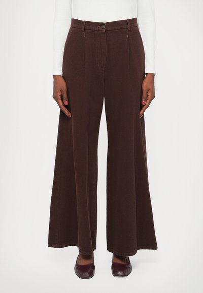 Wide-leg dark brown trousers worn with a white long-sleeve top and dark burgundy square-toe shoes.