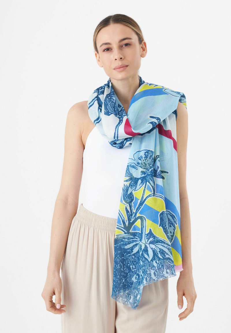 Écharpe à motifs floraux en bleu, avec des accents verts, jaunes et rouges. Fabriquée en tissu léger avec une texture douce, drapée élégamment.