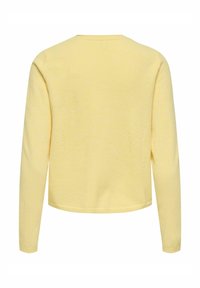 Haut jaune à manches longues avec un col arrondi et un tissu lisse et texturé. Le modèle présente une coupe courte et des poignets côtelés.