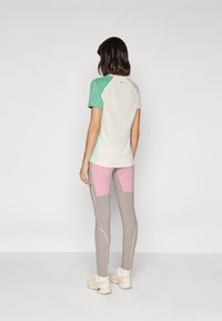 Kortermet aktivt topp med fargeblokkerte grønn, rosa og hvite farger; tettsittende design kompletterer grå og rosa treningstights.