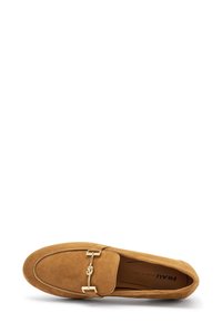 Mocassino in suede color tan con dettaglio in metallo dorato, punta rotonda e cuciture lungo i bordi. Suola flessibile per il comfort.