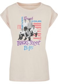 Lyse beige t-skjorte med korte ermer, med et grafisk trykk av fem figurer i svart og hvitt, samt fargerik tekst som leser "Jeg vil aldri knuse hjertet ditt" og "Backstreet Boys."