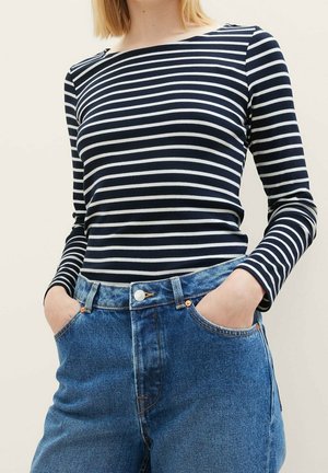 Top a maniche lunghe a righe blu e bianche realizzato in un tessuto leggero, abbinato a jeans in denim blu a vita alta con chiusura a bottone.