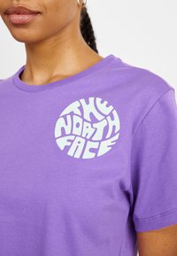 Purple cotton t-shirt featuring a white circular logo with "THE NORTH FACE" text. Regular fit with short sleeves and a round neckline.