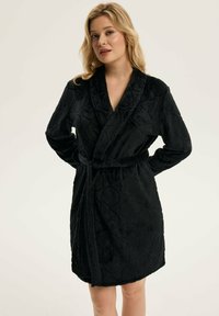 Czarna szata z pluszowego materiału, z wzorem w diamenty, długimi rękawami, paskiem w talii i kołnierzem szalowym. Miękka tekstura i średnia długość.