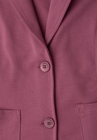 Gros plan d'un blazer mauve avec deux boutons étiquetés Street One et deux poches avant.