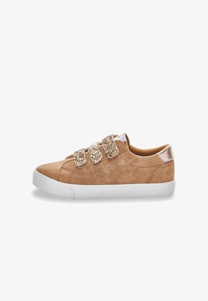 Baskets en suède beige avec trois bandes Velcro scintillantes, semelle en caoutchouc blanche et accents texturés sur le talon et les orteils. Conçues pour une utilisation décontractée.