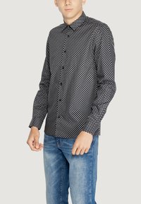 Camicetta a maniche lunghe a righe bianche e nere, con colletto e vestibilità slim, abbinata a jeans blu classici.