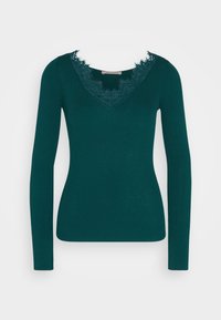Haut en maille côtelée vert foncé à manches longues avec encolure en V et bordure en dentelle autour du col, silhouette ajustée.