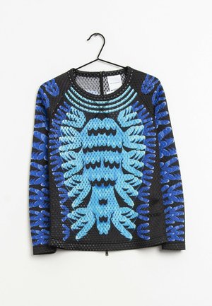 Top negro de manga larga de malla con patrones azules abstractos simétricos de hojas, cuello redondo y cremallera en la espalda, colgado en una percha negra.