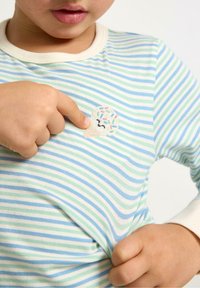 Chemise à manches courtes rayée en tissu doux, avec des lignes bleues et vertes. Comprend un patch en forme de cornet de glace avec des vermicelles sur la poitrine.