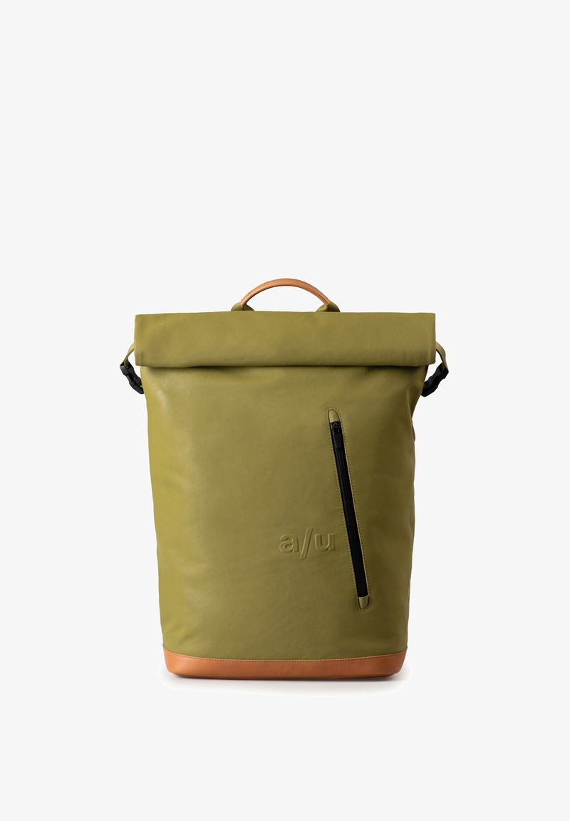 Zaino a sacca verde realizzato in tessuto strutturato, con una tasca con zip nera e una base in pelle marrone con manico superiore.