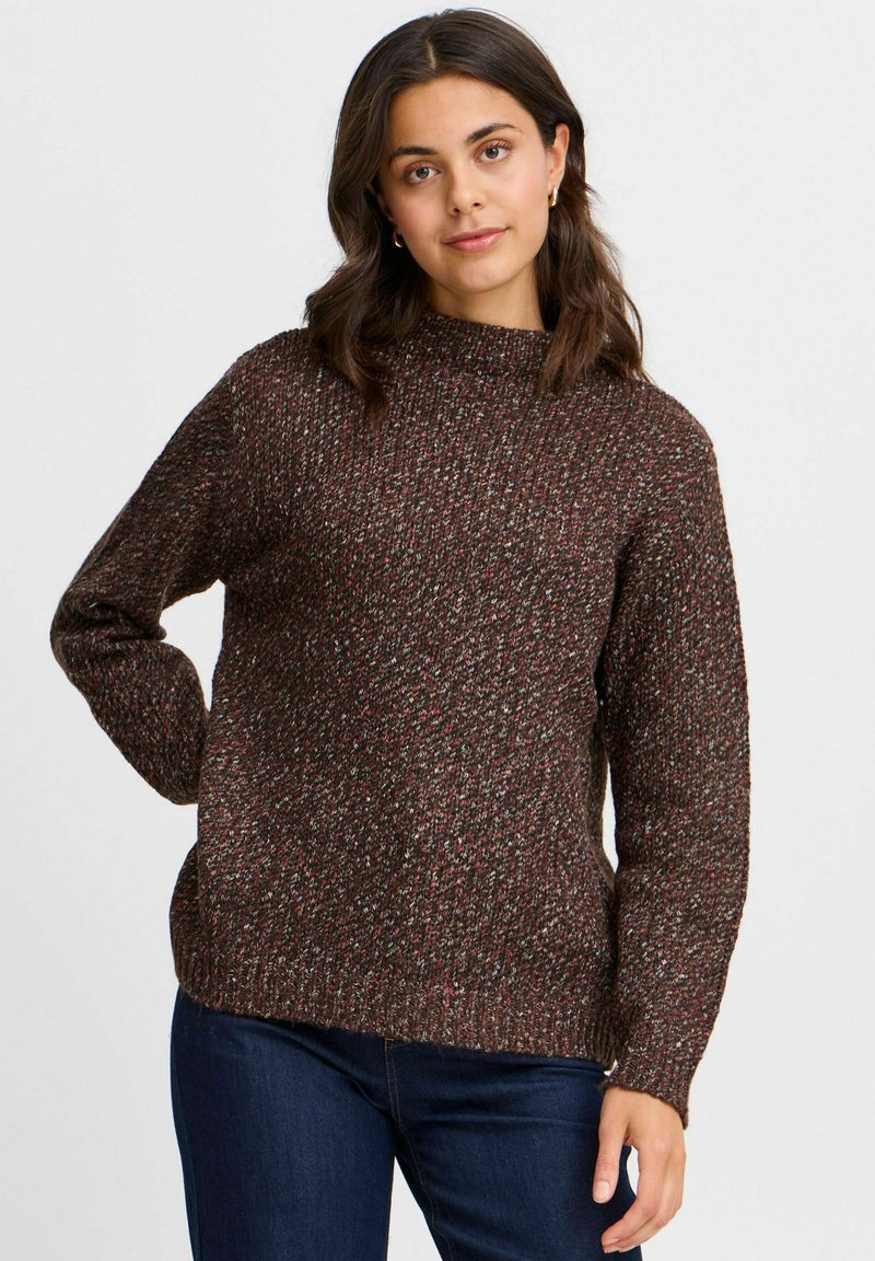 Maglione marrone a trama con collo alto, caratterizzato da un motivo a maglia a righe multicolori, abbinato a jeans blu scuro.