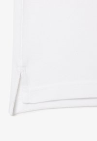 Tissu en coton blanc avec une surface texturée, comportant un ourlet cousu et un détail d'ouverture sur le côté pour un meilleur confort de mouvement.