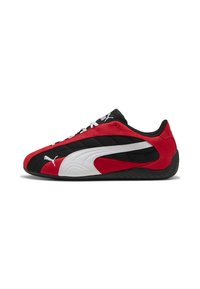 Zapatillas deportivas rojas y negras con una parte superior texturizada, que presentan un logo de swoosh blanco, cierre de cordones y una suela de goma negra.