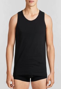 Top in cotone nero, caratterizzato da un colletto rotondo e spalline larghe, design aderente e texture liscia. Stile minimalista, senza fantasie.