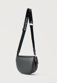 Μαύρη δερμάτινη crossbody τσάντα με φαρδιά ρυθμιζόμενη τιράντα που φέρει λευκή επιγραφή "VALENTINO" και επίχρυσα μεταλικά στοιχεία σε απλό ανοιχτό φόντο.