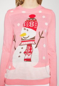 Rosa gestrickter Pullover mit einem Schneemann-Motiv, der einen roten gestrickten Hut, einen gemusterten Schal und verstreute weiße Schneeflocken zeigt.