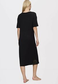 Czarna sukienka do kolan z krótkimi rękawami, wykonana z miękkiego materiału. Posiada koronkowe akcenty na dolnym brzegu oraz okrągły dekolt.
