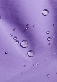 Waterafstotende paarse stof met een gladde textuur, voorzien van verschillende maten waterdruppels verspreid over het oppervlak.