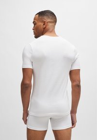T-shirt bianca aderente a maniche corte realizzata in morbido cotone, con scollatura a girocollo e una leggera texture, abbinata a boxer bianchi.