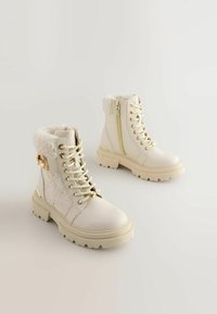Witte faux leren enkellaarzen met een pluizige kraag, gouden hardware, textuurdesign, vetersluiting aan de voorkant en een ritsdetail aan de zijkant.