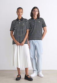 Polo cu dungi alb-negru; unul cu o fustă albă pliată, iar celălalt cu blugi albaștri deschiși și pantofi albi. Accesorii simple.