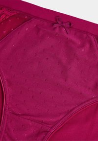 Mutande fucsia con una texture liscia e a pois e dettagli in pizzo. Presenta un fiocco in vita e orli elastici.