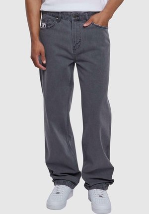 Grå denim jeans med løs passform, med synlige sømmer, sidelommer og knappelukking foran. Kombinert med hvite sneakers.