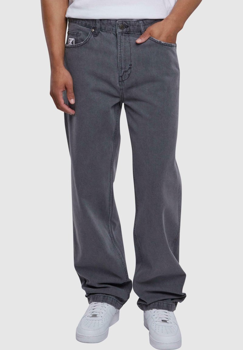Grå denim jeans med løs passform, med synlige sømmer, sidelommer og knappelukking foran. Kombinert med hvite sneakers.