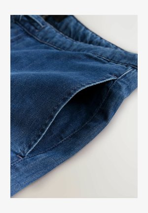 Denimjeans in mittlerem Blau, mit weicher Textur, Standardtaschendesign und sauberer Nahtführung entlang der Kanten.