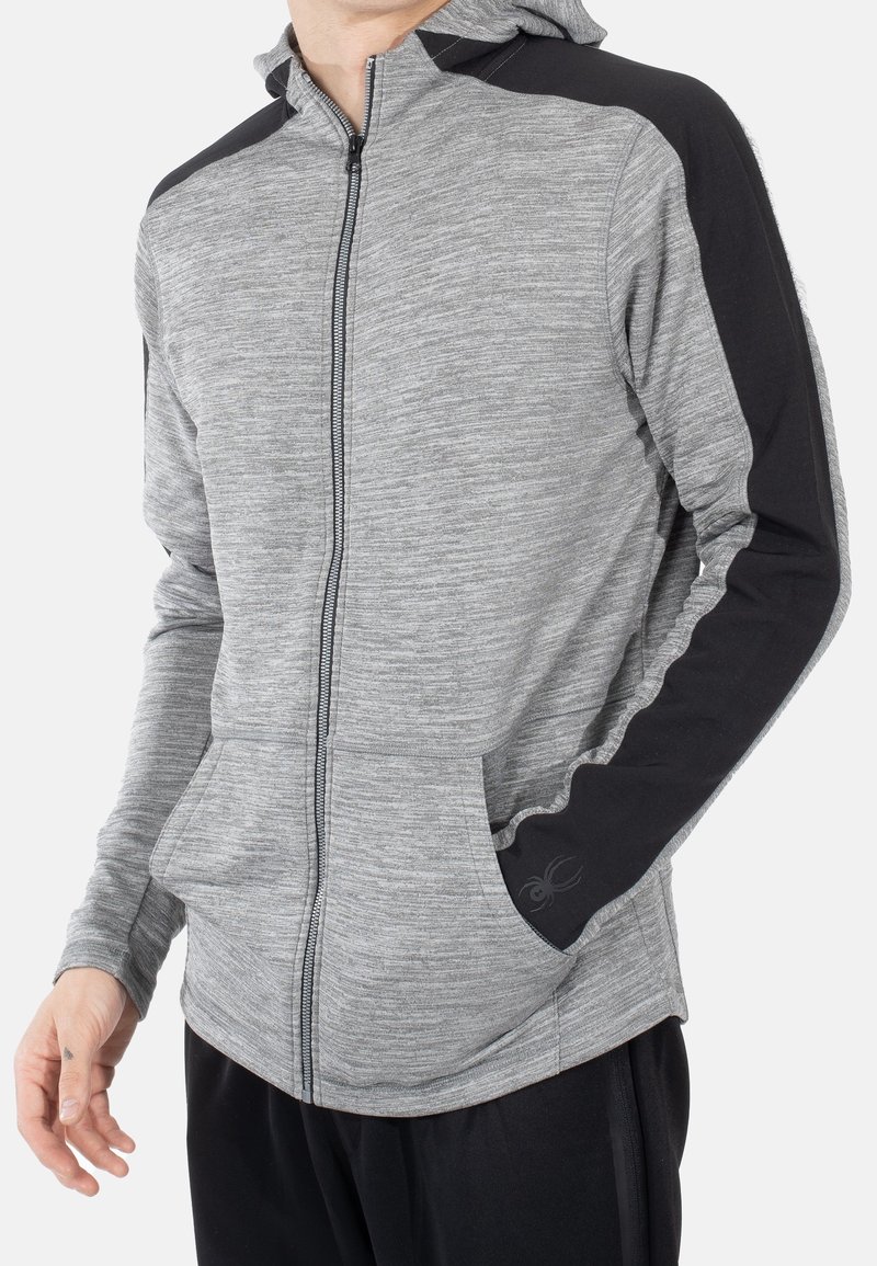 Sudadera con cremallera en color gris que presenta acentos en negro en los hombros y los puños, fabricada con una tela texturizada que incluye un bolsillo tipo canguro y un detalle de logo.