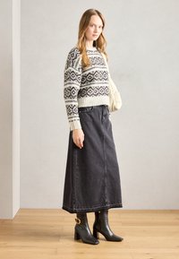 Knit sweater with a black and white geometric pattern, paired with a black long denim skirt and black heeled ankle boots with gold accents.