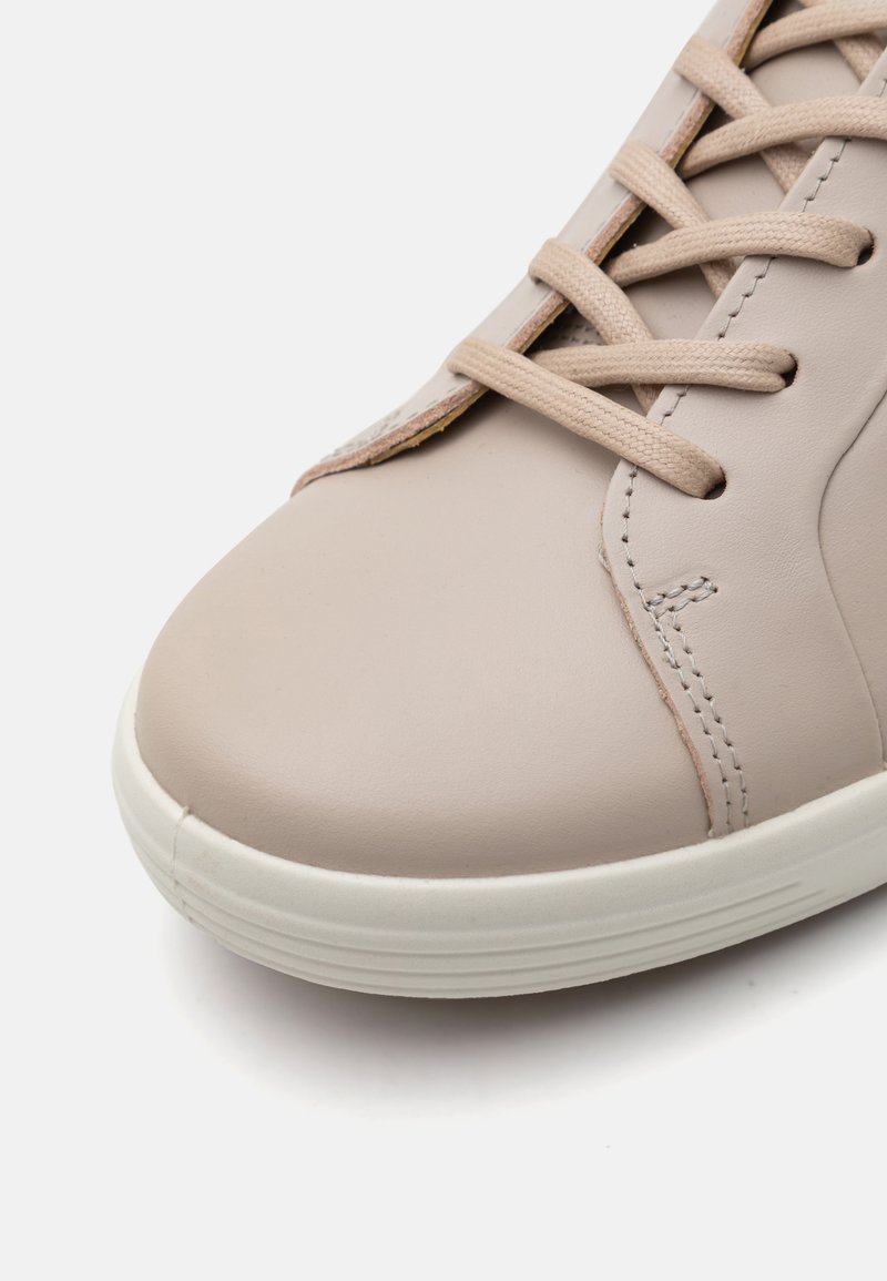 Beige Leder Sneaker mit strukturierter Oberfläche, runder Zehenpartie und beigen Schnürsenkeln. Verfügt über eine weiße Gummisohle mit dezenten horizontalen Rillen.
