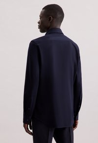 Camicia a maniche lunghe blu navy realizzata in tessuto liscio, con colletto classico, polsini con bottoni e orlo curvo per un fit rilassato.