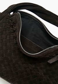 Borsa in suede nero con trama intrecciata, caratterizzata da una chiusura con cerniera e una fodera interna liscia. Etichetta del marchio visibile all'interno.