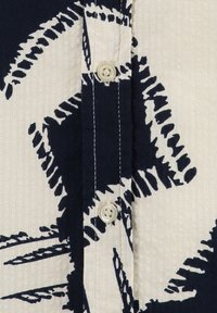 Marineblaues und cremefarbenes Knopfhemd aus strukturiertem Stoff mit einem auffälligen botanischen Muster und einer klassischen Knopfleiste.