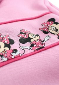 Tissu rose avec trois images imprimées d'un personnage portant une robe à pois et un nœud, présentant différentes poses et expressions faciales.