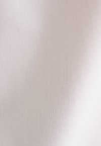 Texture di tessuto beige chiaro, liscia, con un motivo a trama fine e ombreggiature sottili, illuminata in modo uniforme senza pieghe o grinze visibili.