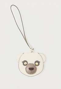 Λευκό δερμάτινο μπρελόκ σε σχήμα προσώπου αρκούδας με καφέ λεπτομέρειες, χρυσά κουμπιά για μάτια και μαύρη θηλιά για στήριξη.