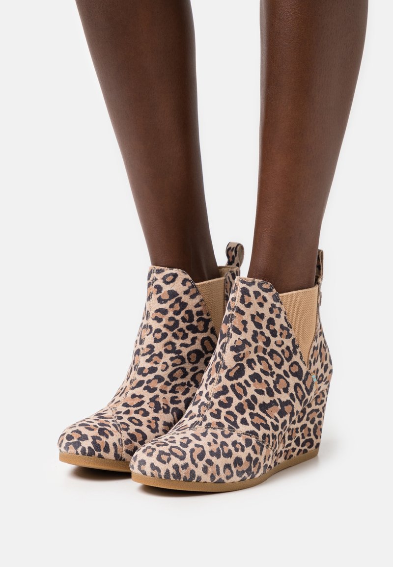 Bottines à talons compensés en imprimé léopard avec une texture en suède doux, des panneaux élastiques sur les côtés et un design à bout rond. Semelle marron clair.