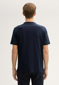 T-shirt bleu marine en tissu lisse, avec un col rond classique et des manches courtes, un ourlet droit et des détails de couture minimalistes.