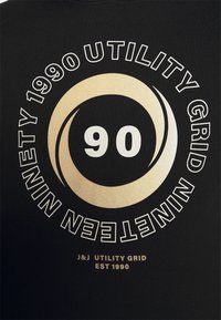 Camiseta de algodón negra con un diseño gráfico en texto en negrita dorado y blanco que presenta "90", "UTILITY GRID" y "1990" en un disposición circular.