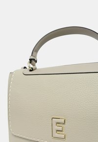 Borsa a mano in pelle beige chiaro con un design strutturato, manico superiore, hardware in oro e accenti di cuciture bianche. Presenta una lettera "E" ben visibile.