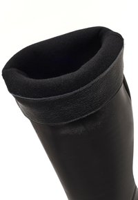 Stivale impermeabile nero in gomma con morbida fodera in pile nera e una strap nera testurizzata nella parte superiore per una maggiore aderenza e comfort.