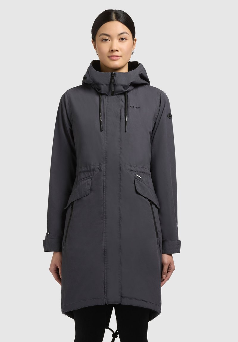 Parka impermeabile grigia, dotata di cappuccio, chiusura frontale con zip, due tasche anteriori, lacci regolabili in vita e maniche con bottone.