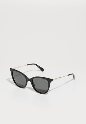 Svart cat-eye-solglasögon med mörka linser. Har tunna guldfärgade metallaccenter vid bågarna och en slät, glansig ramfinish.