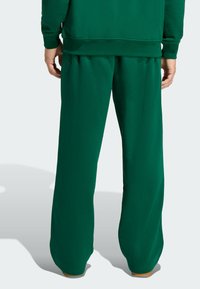 Zielone dresy z luźnym krojem, wykonane z miękkiego materiału. Posiadają elastyczny pas i zwężane mankiety. Brak widocznych wzorów lub akcentów.