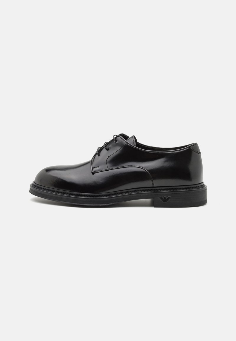 Scarpa da dress in pelle nera con finitura liscia, punta arrotondata e lacci. Presenta una suola nera spessa e un sottile dettaglio di cucitura lungo il bordo.