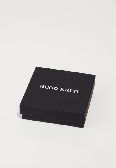 Scatola rettangolare nera con finitura opaca, dotata della scritta "HUGO KREIT" in rilievo bianco, che mostra un design minimalista e una superficie liscia.